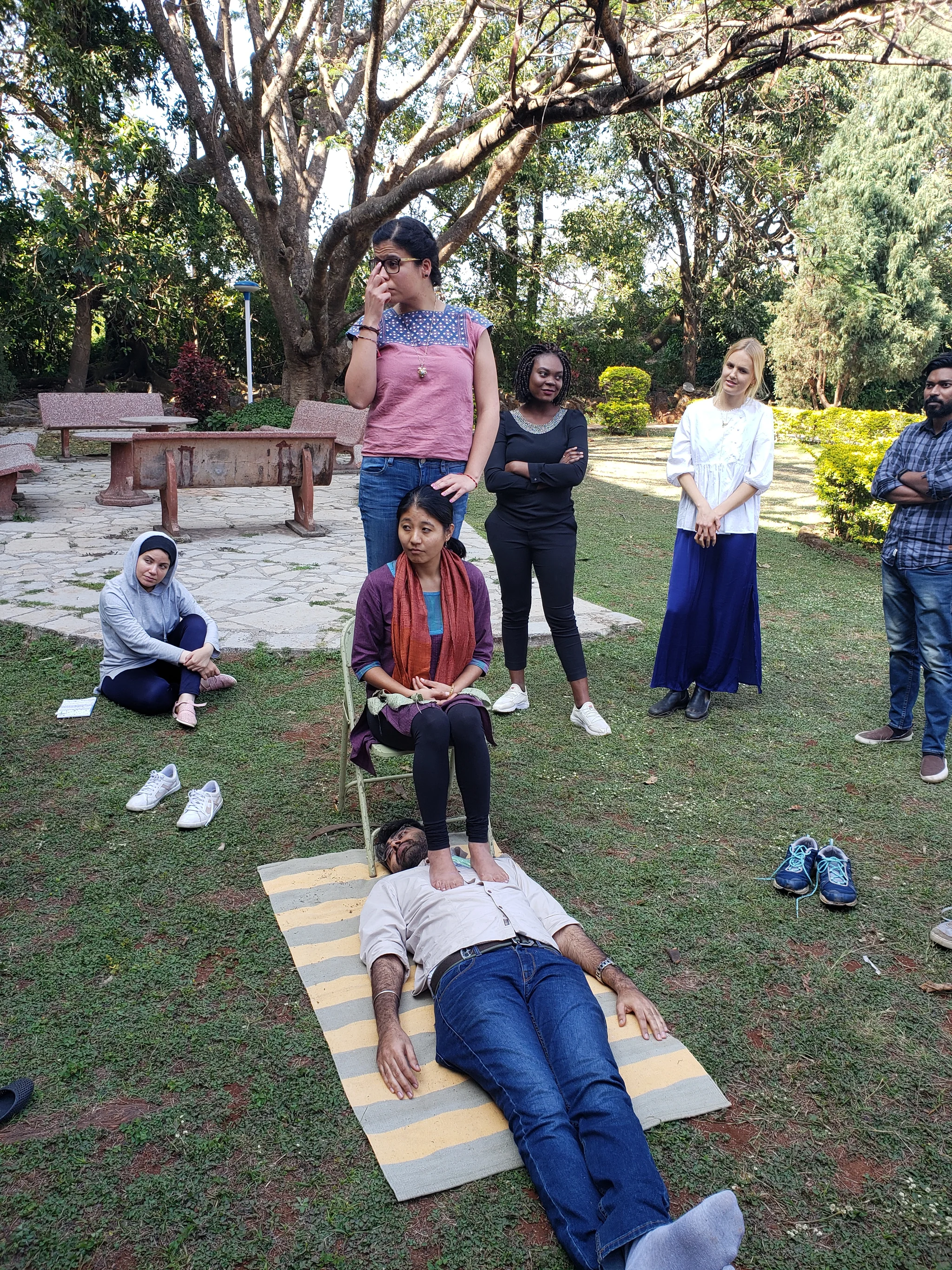 People participating in an outdoor group exercise under trees.
