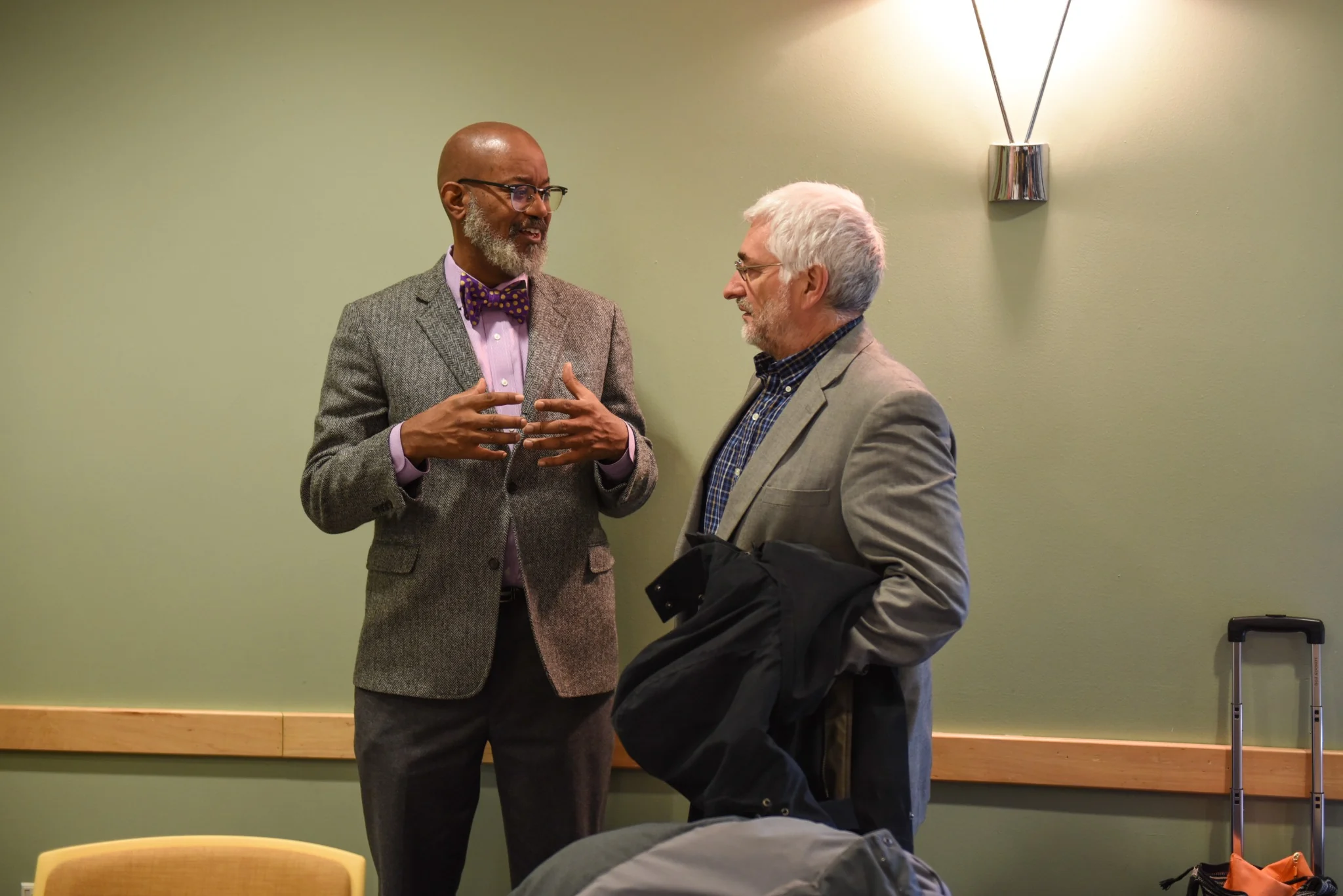 David in conversation with another man in a meeting room.