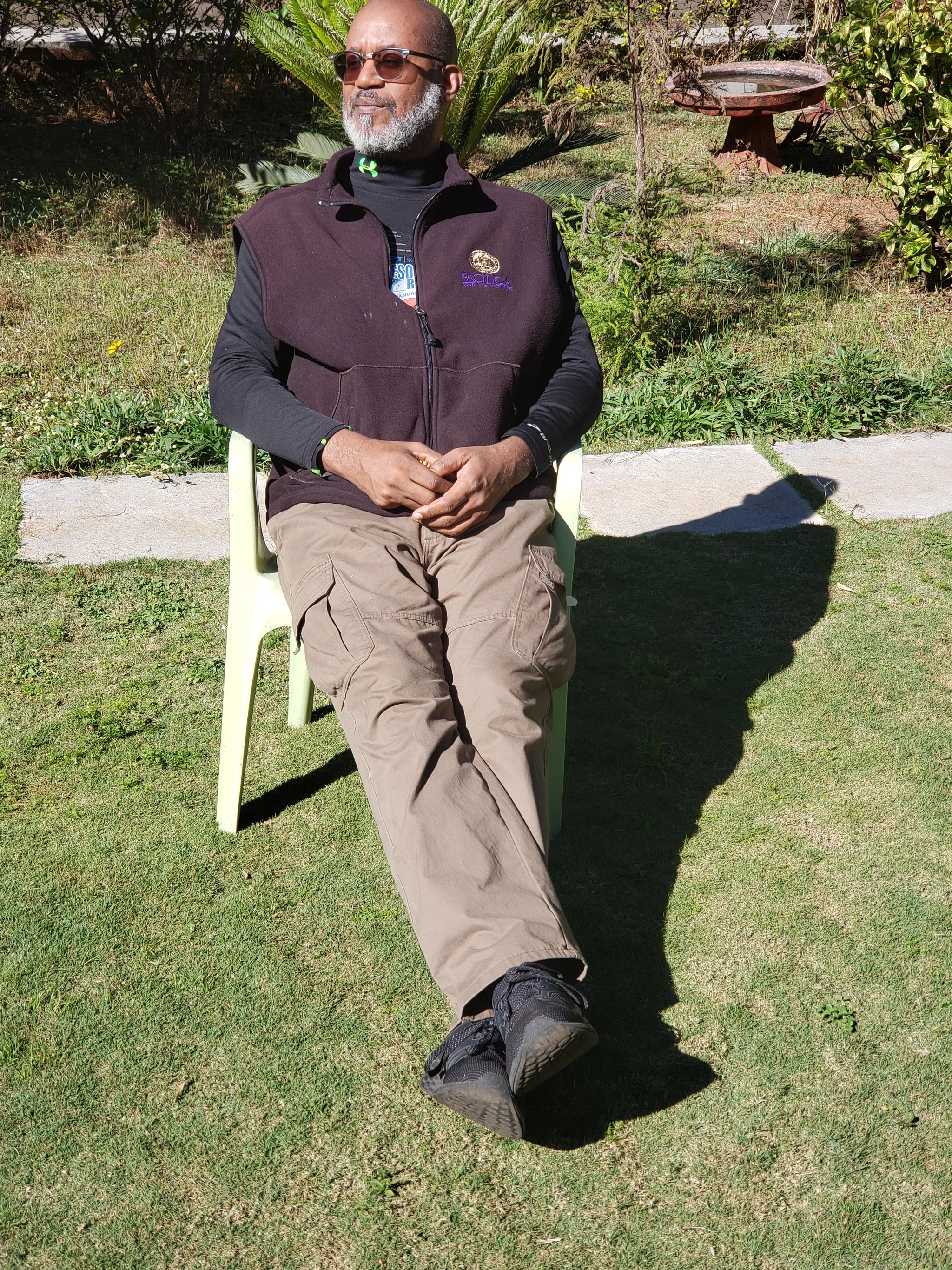 David seated outdoors, shown full length with his feet and the surrounding ground visible