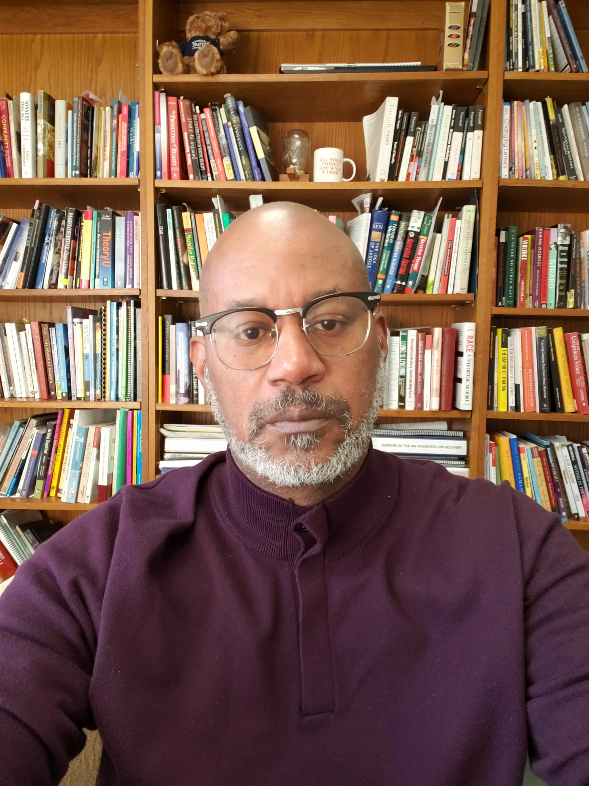 David seated in front of shelves of books