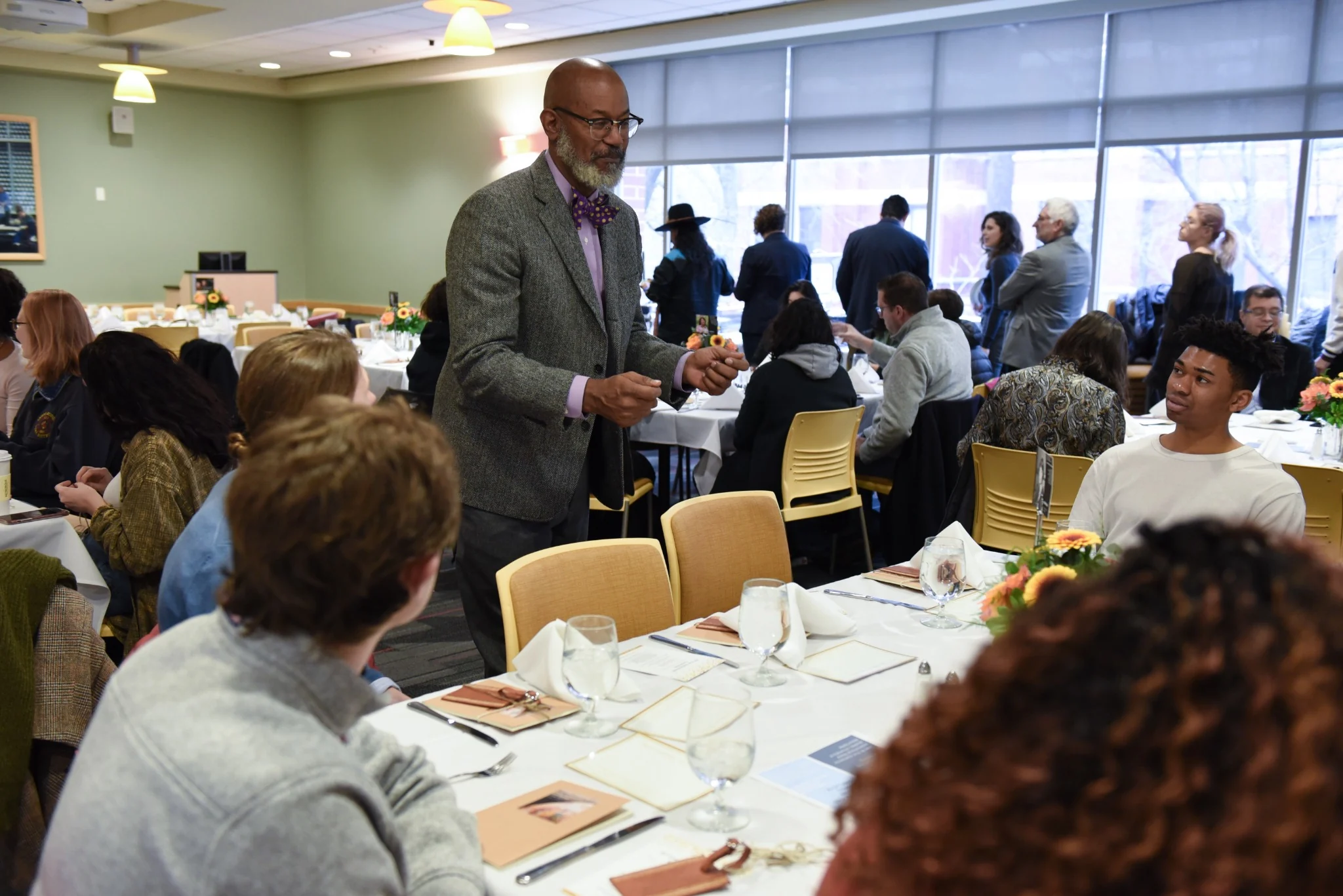 David facilitating among participants seated around tables in a bright meeting room.
